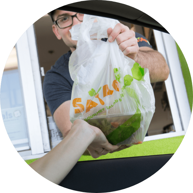 A Salad and Go team member handing a salad through the drive-thru window