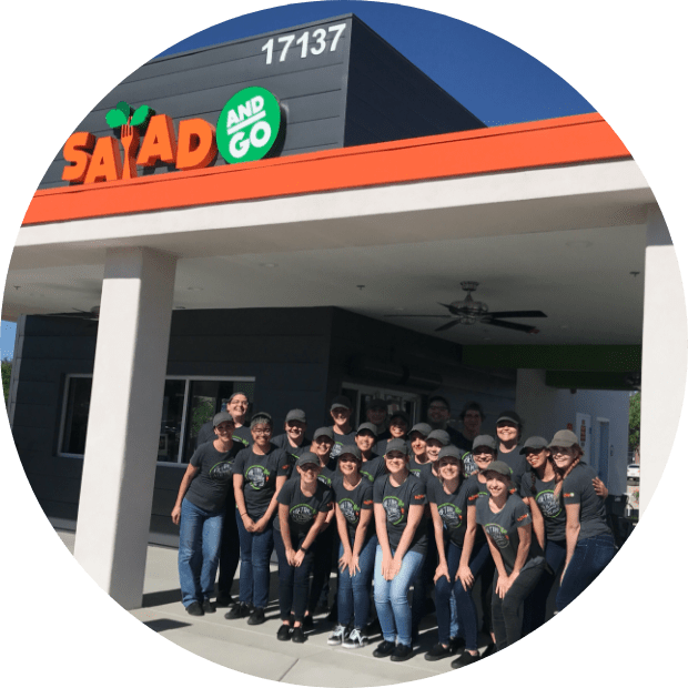 Smiling Salad and Go Team Members in front of a Salad and Go restaurant location.