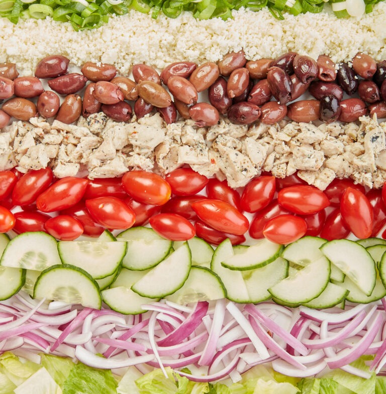Deconstructed Greek salad with ingredients laid out in rows